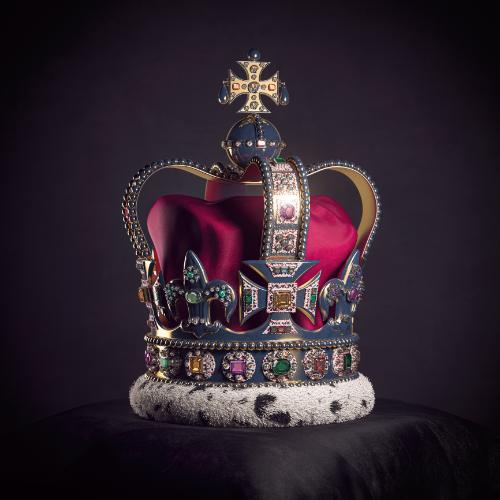 Królewska złota korona z klejnotami na poduszce na czarnym tle. Symbole brytyjskiej monarchii Wielkiej Brytanii. (Fot. iStock)