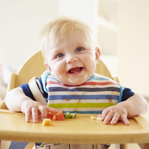 31046318 - baby boy eating fruit in high chair