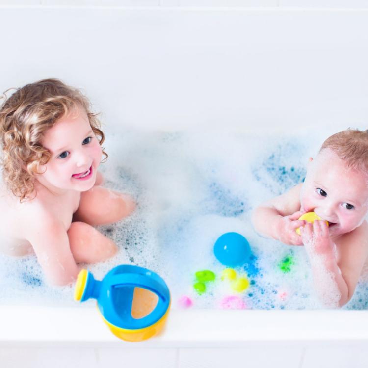 30966340 - funny little girl and her cute baby brother having fun taking bath together playing in water with foam with colorful toys after shower