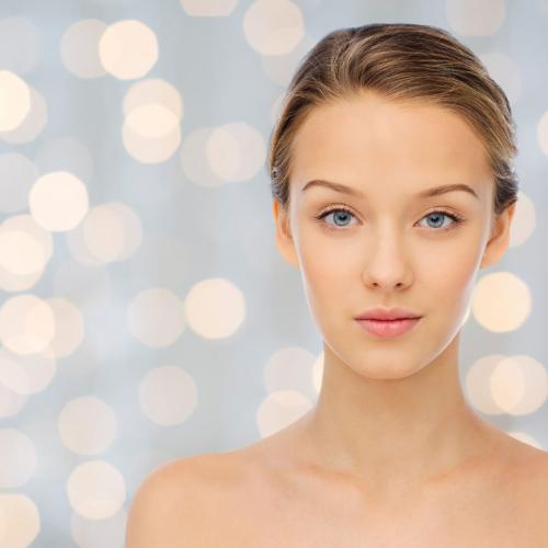 51385373 - beauty, people and health concept - young woman face and shoulders over holidays lights background
