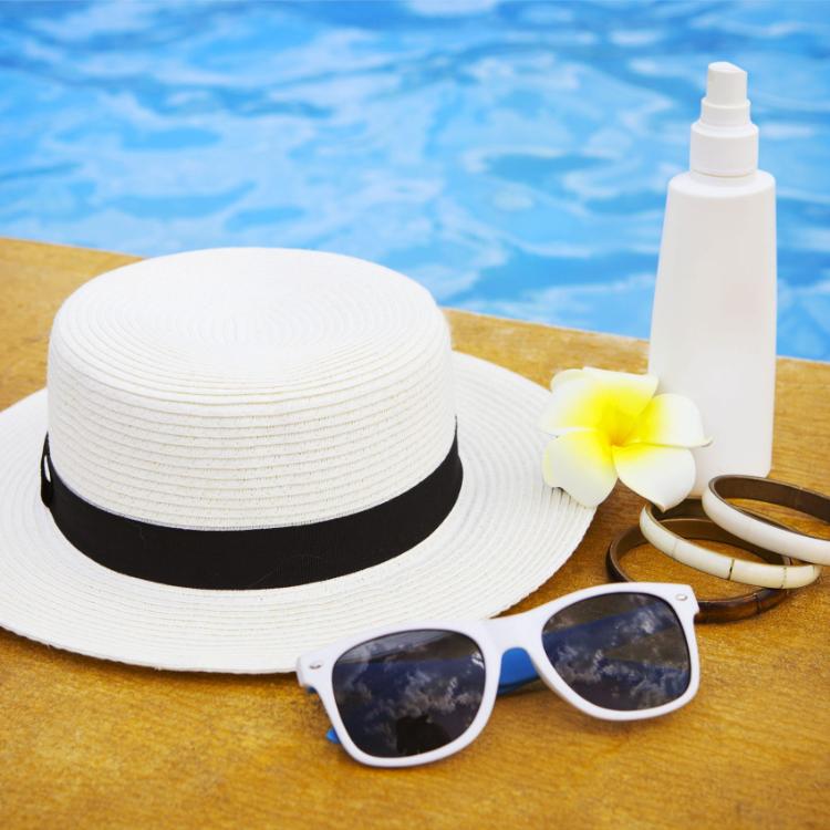 57290419 - suncream, sunglasses, hat, bracelet near the swimming pool. vacation concept
