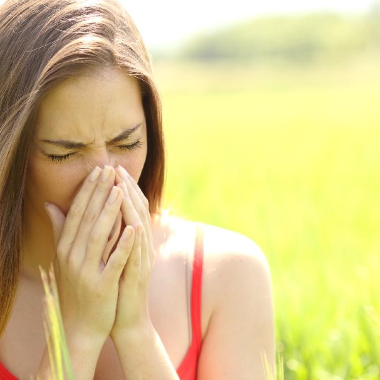 Woman with allergy coughing in a field