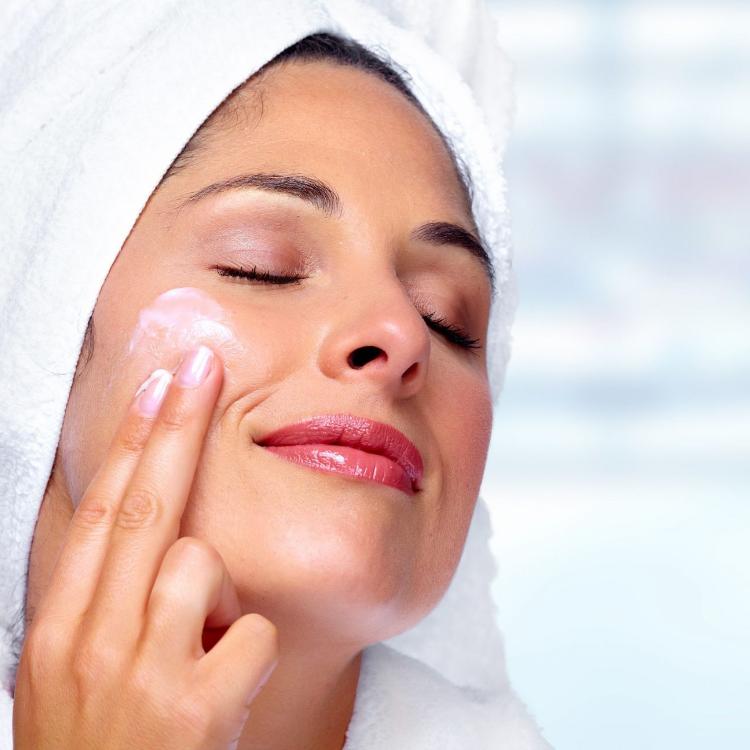 Beautiful woman face with moisturising cream. Skin care background.