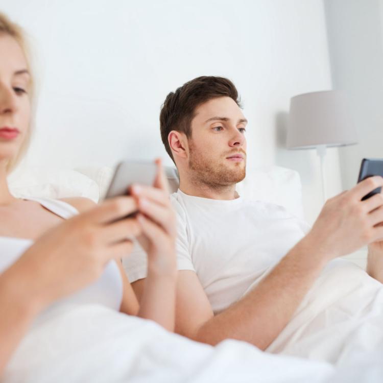 62181122 - people, technology, internet and communication concept - couple with smartphones in bed