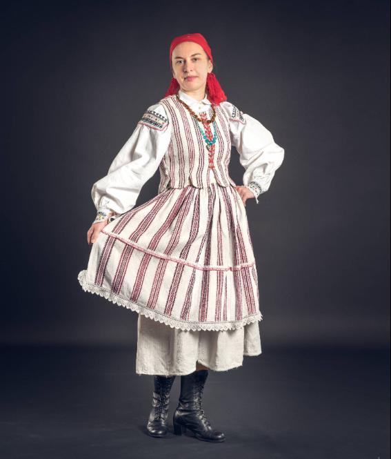  Jolanta Kagankiewicz prezentuje lniany strój letni noszony na przełomie XIX i XX wieku. Ubrana jest w koszulę o przyramkowym kroju, haftowaną na „przyramkach” i mankietach haftem przeszywanym, w przeważającym czarnym kolorze; „sorc”, czyli spódnicę w pas z tkaniny lniano-bawełnianej tkanej w tzw. „koziełki”, „zapołową” zapaskę do pasa obszytą „korunką” wykonaną w czerwono-czarne „koziełki” oraz gorset z tackami, rozcinany i sznurowany atłasową wstążką. Strój zdobią korale z „kościokiem”, czyli medalikiem z jasnogórskim wizerunkiem, płócienna chustka z frędzlami, wyszywana haftem płaskim oraz czarne, skórzane trzewiki. (Fot. Tomasz Jóźwik/materiały prasowe Folk Fashion Show)