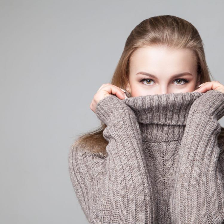 49556584 - beautiful blond young girl wears winter pullover over gray background