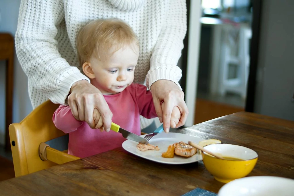 Mama pomaga rocznemu dziecku w nauce samodzielnego jedzenia Fot. Materiały partnera