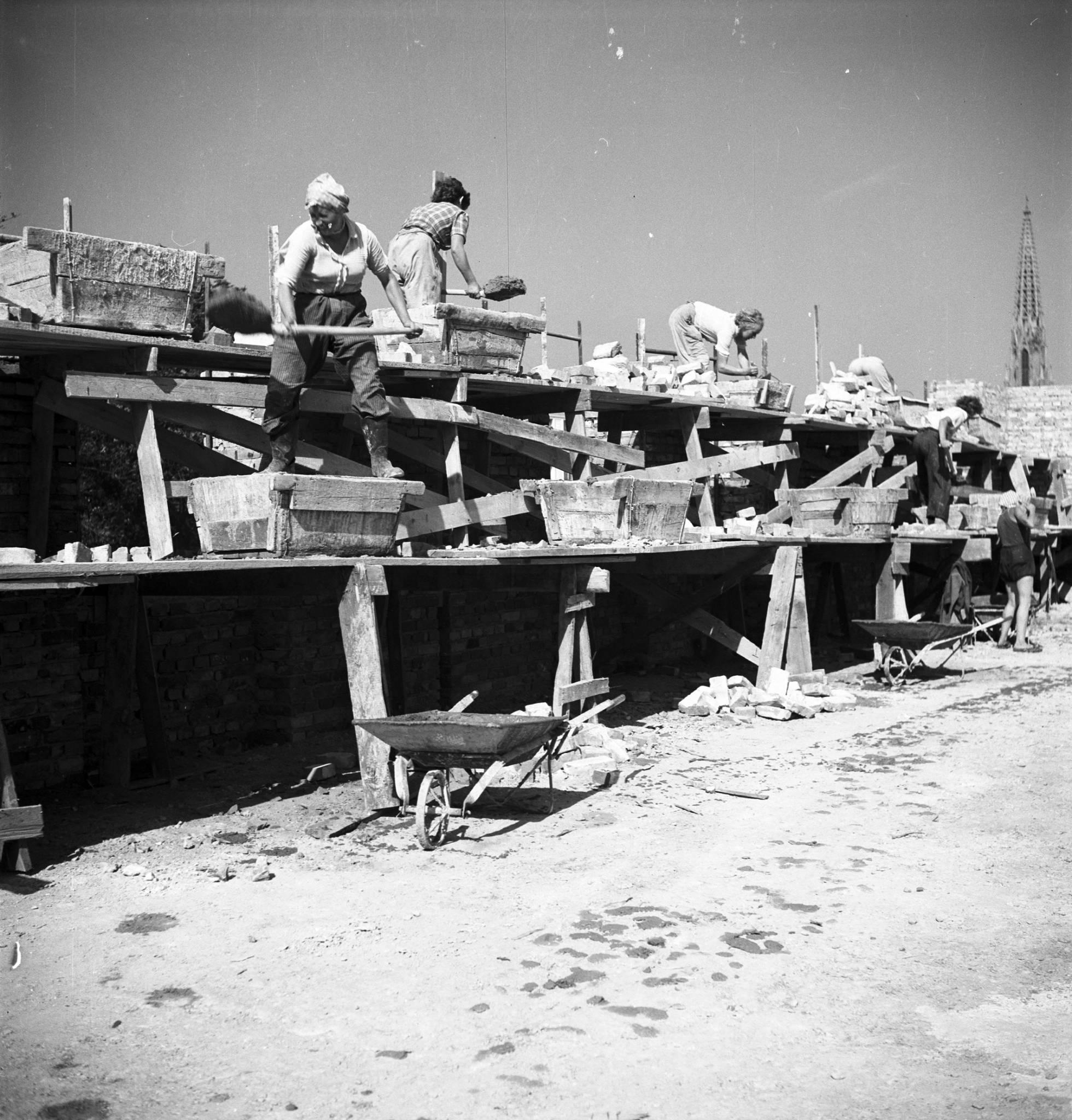  5) Brygada kobieca budująca blok mieszkalny. Na dalszym planie widoczna wieża kościoła ewangelicko-reformowanego, 1952 – 1959, fot. Siemaszko Zbyszko NAC