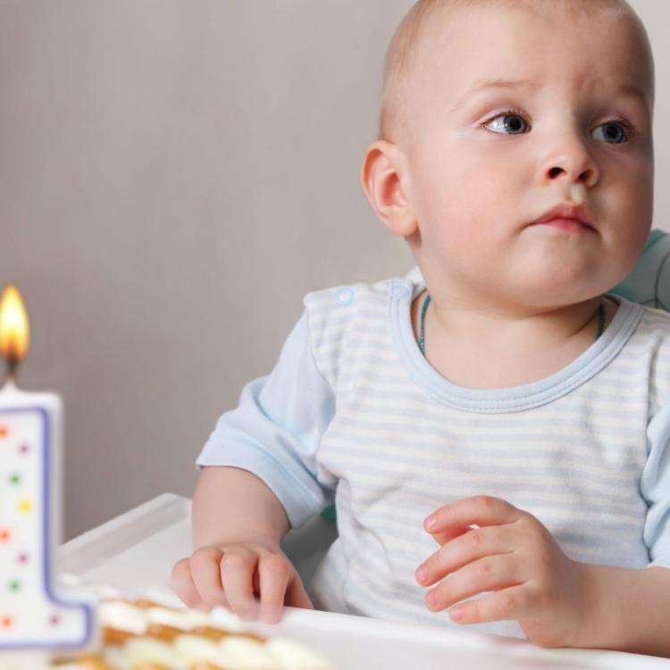 12732401 - little baby celebrating its first birthday, in front of him cake with candle