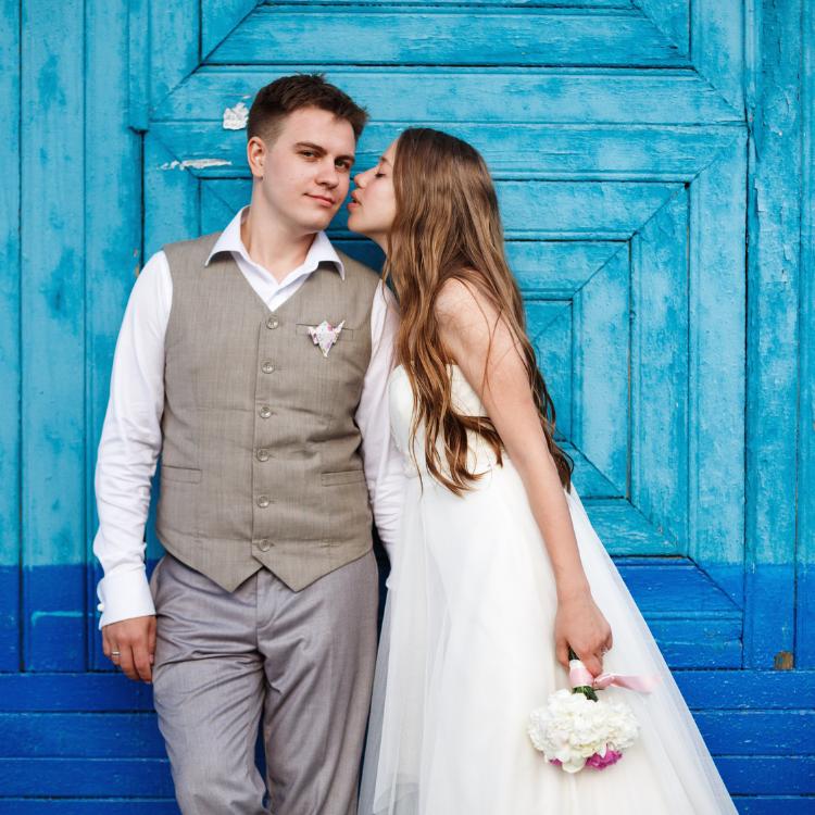 Happy stylish wedding couple having fun against blue background