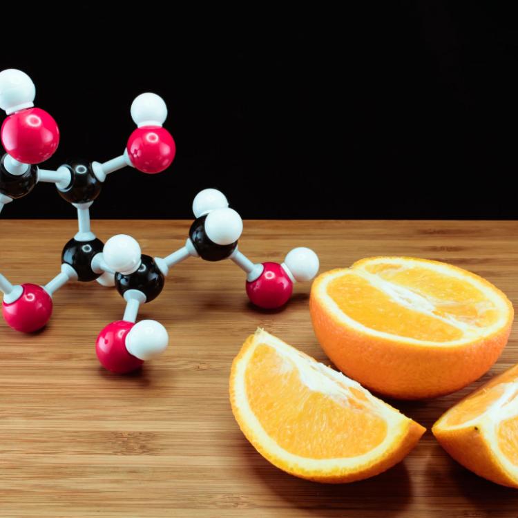 38558982 - orange and vitamin c structure model (ascorbic acid) on wood with black background