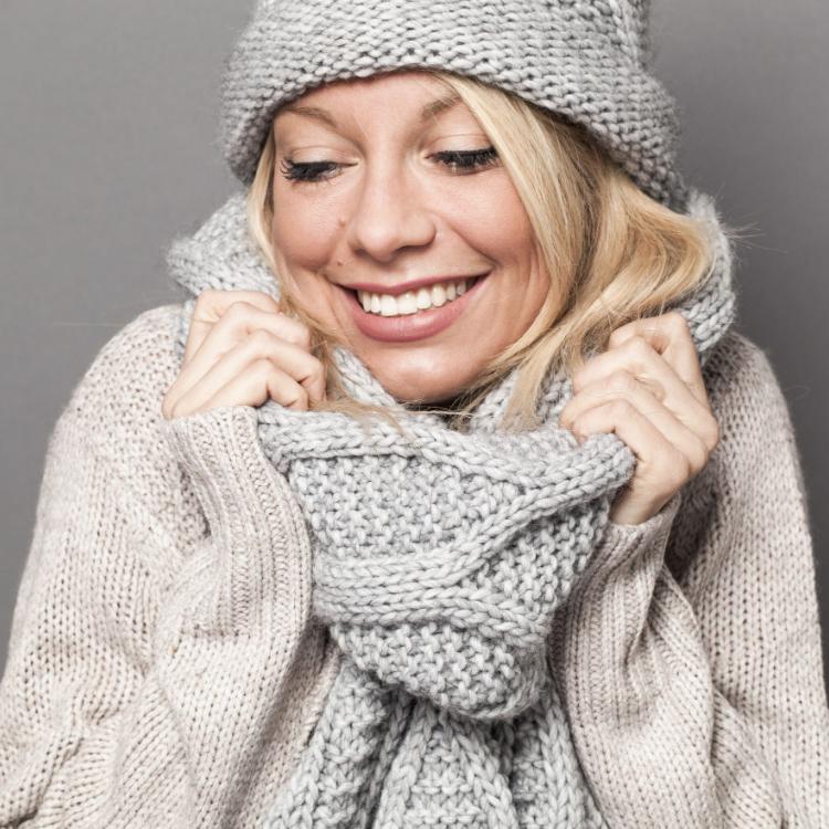 47014101 - trendy warm winter - gorgeous young blond woman wrapping up herself in gray wool winter hat and scarf smiling for softness and cozy fashion