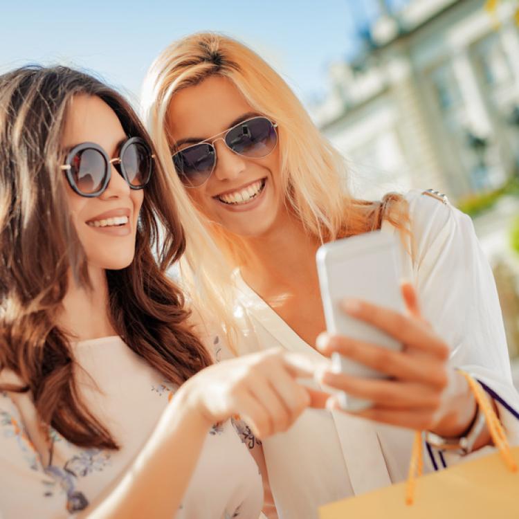 Beautiful smiling girls making selfie after good shopping