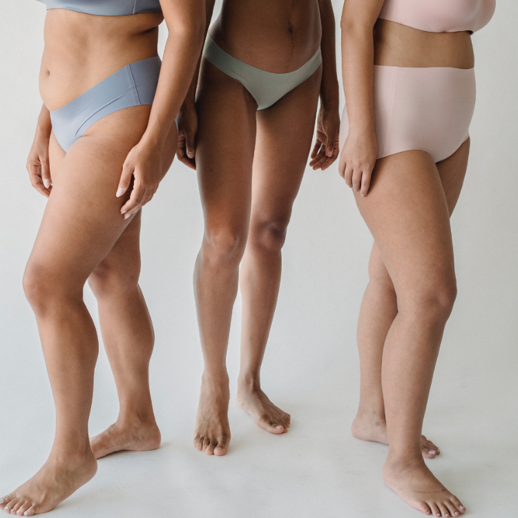 Trzy kobiety stoją w bieliźnie. Mają widoczne niedoskonałości oraz cellulit. (Fot. pexels.com)