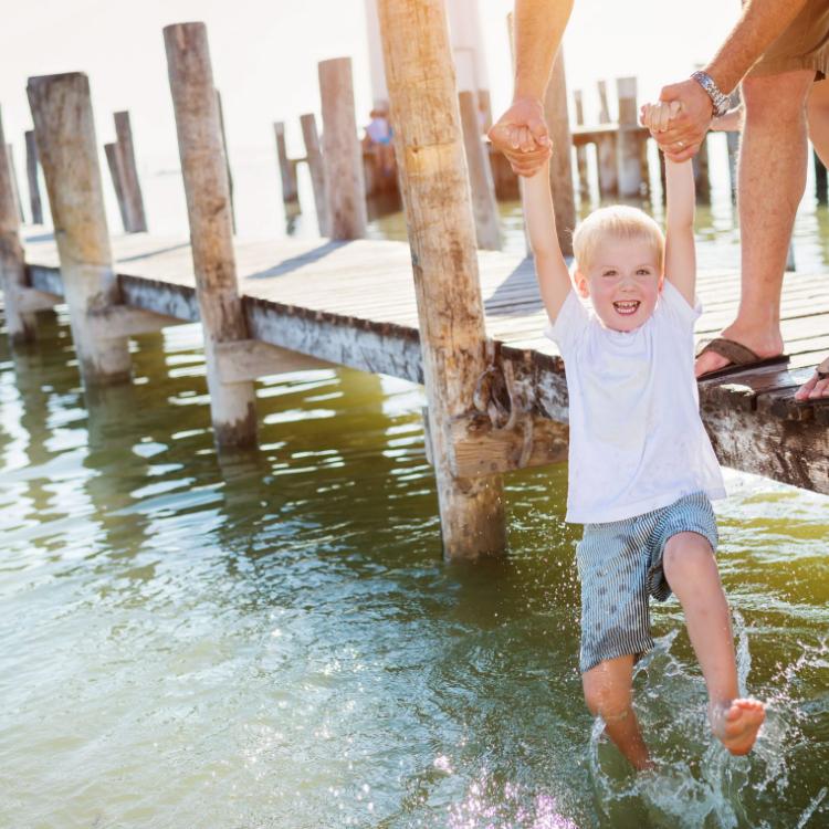 51994586 - father standing on the pier holding his son above water on sunny summer day