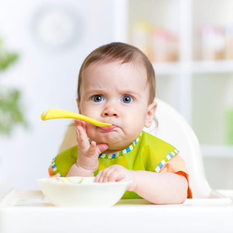 40868780 - funny baby girl eating food on kitchen