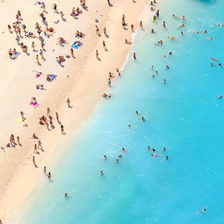 Tourists on the sand beach of Navagio Zakynthos Greece.