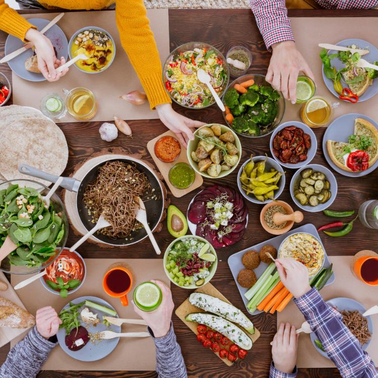 Stół na przyjęciu zastawiony wegańskim jedzeniem: hummusem, sałatkami, warzywami, masłem wegańskim (Fot. materiały partnera)