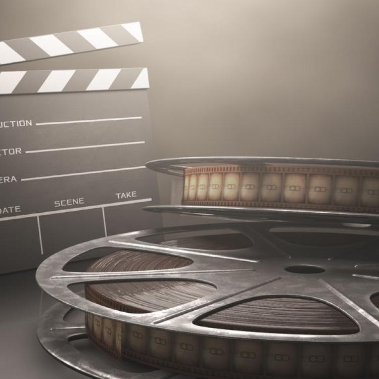 29825707 - clapperboard with rolls of film in the retro concept cinema.